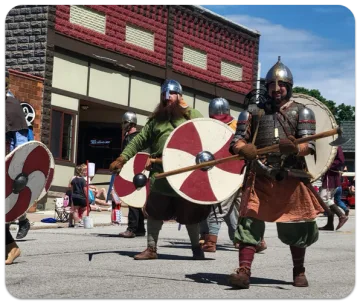 Viking reenactors marching down Main Street with shields and helmets