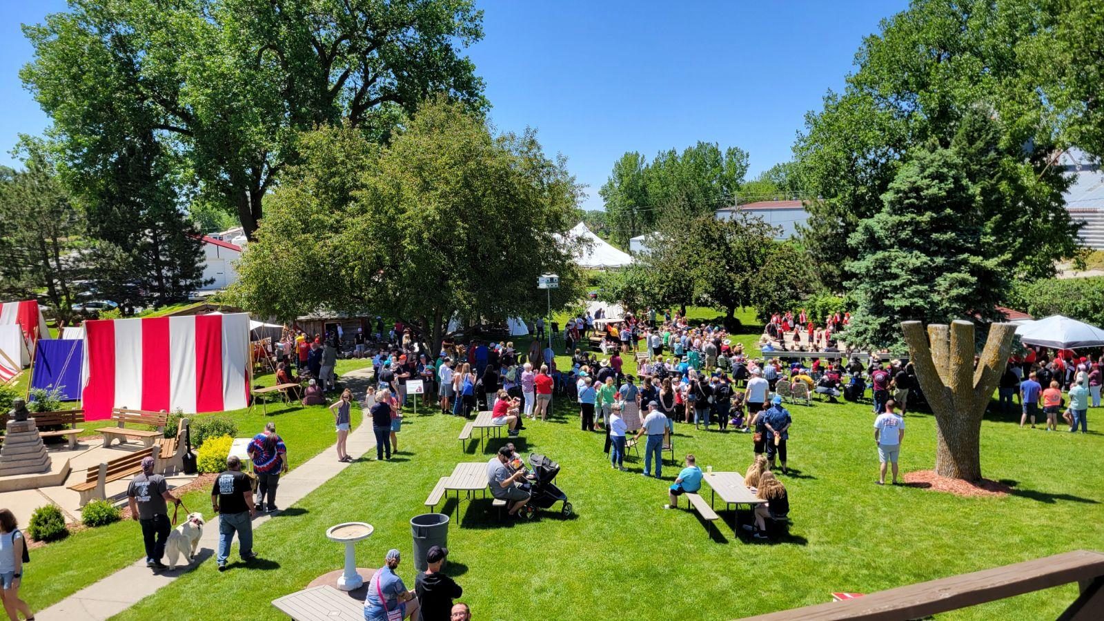 Crowd seated on a lawn watching an outdoor event.