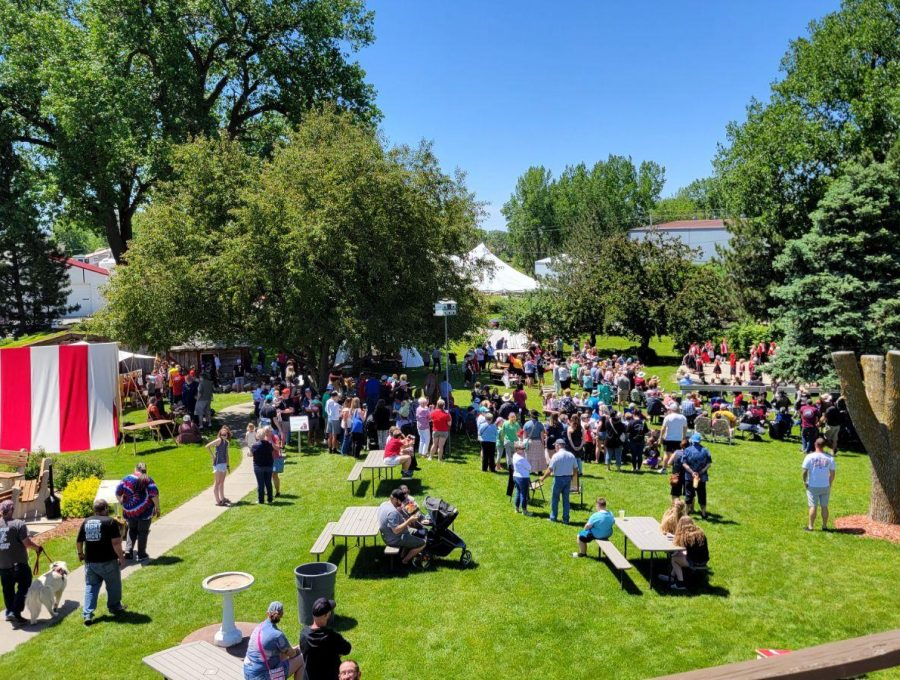 Crowd seated on a lawn watching an outdoor event.
