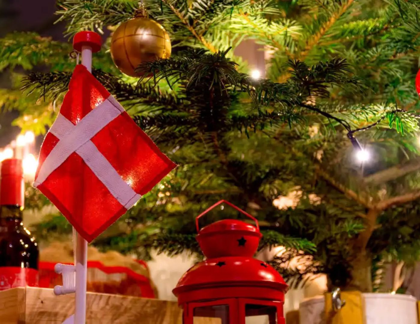 Danish flag ornament and red lantern hanging near a decorated Christmas tree.